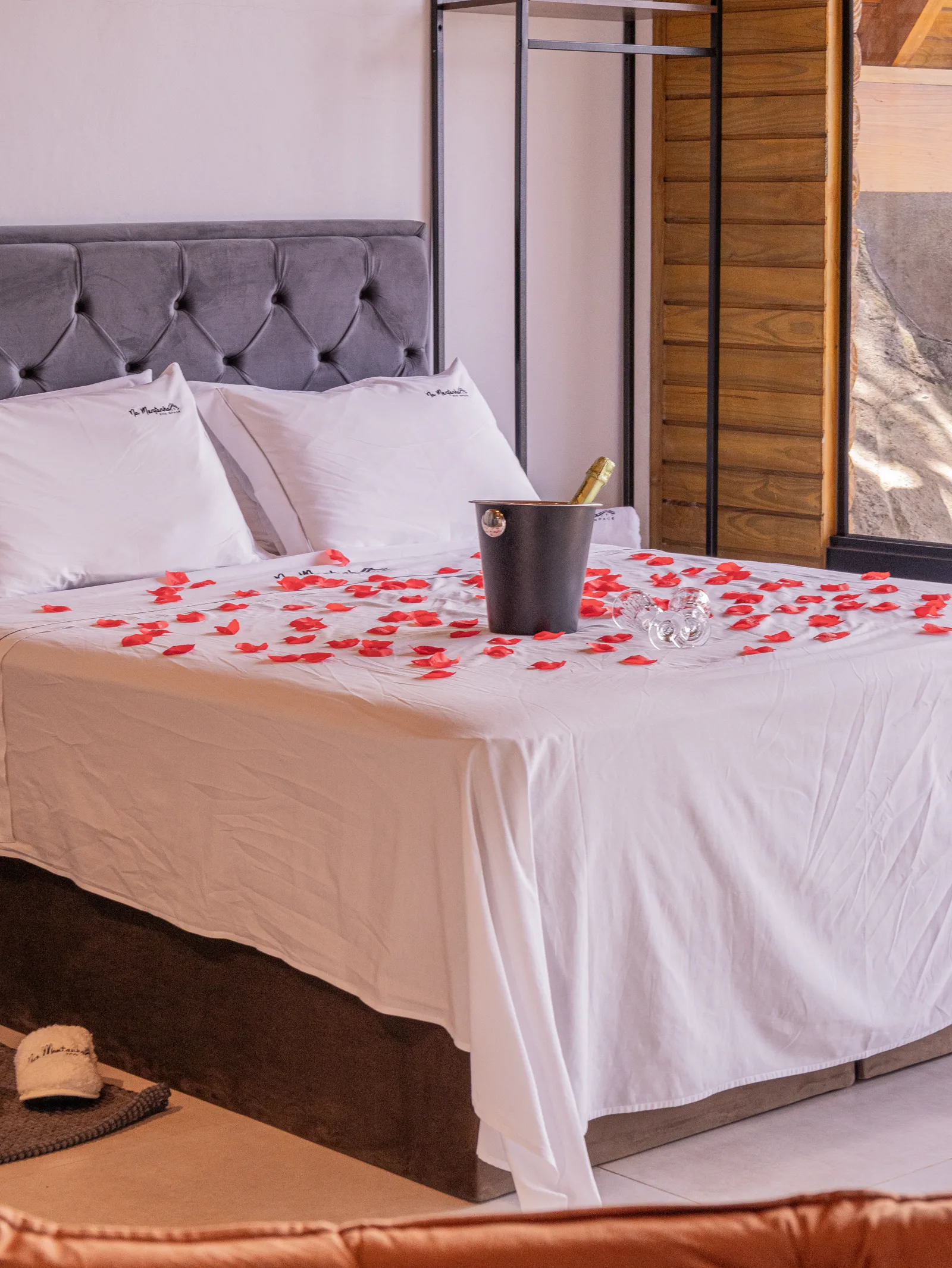 Cama com pétalas, espumante e taças preparados para ocasião especial