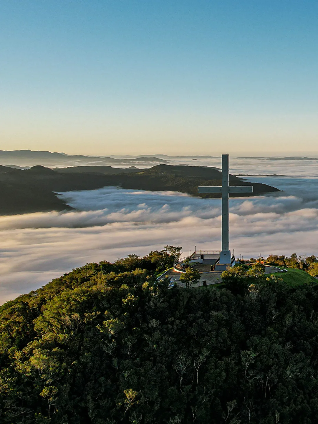 Vista aérea da cruz do Monte da Fé, acima do mar de nuvens